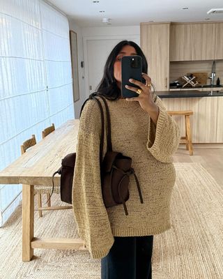 Monikh wears a beige jumper and carries brown bag