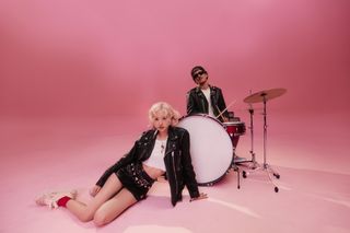 Singer ROSÉ sits on the floor in front of a drum kit, with Bruno Mars behind the drums, in the album art for "APT."