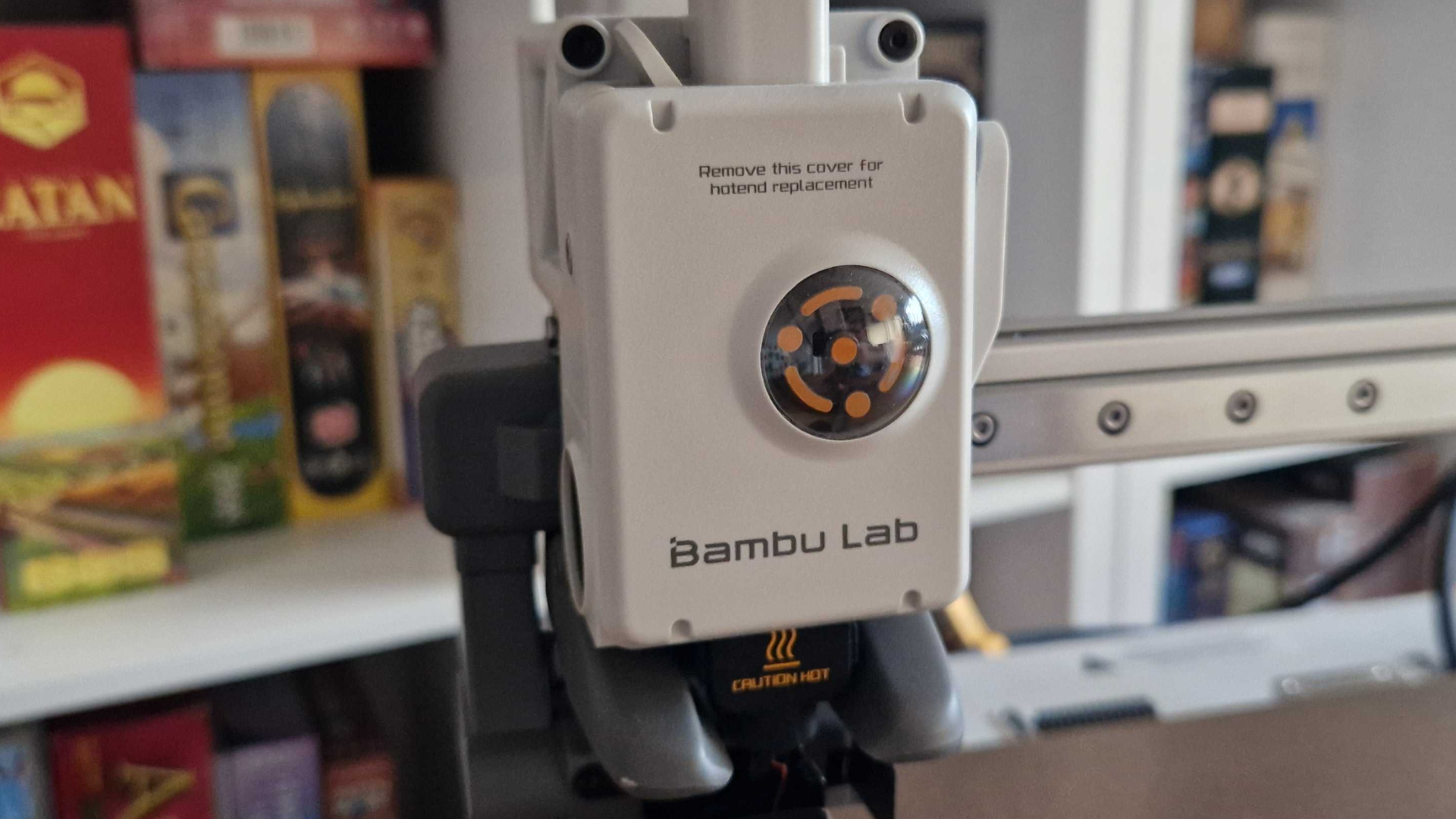 The Bambu Lab A2L printhead, with board games stacked in the background
