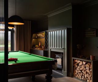 games room with fireplace, pool table and built in shelving to alcove with logs one side and bar area the other all painted in dark grey