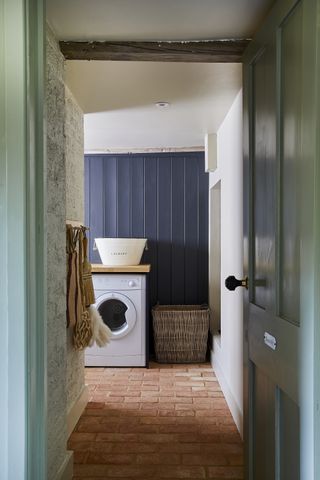 small laundry room ideas blue wood paneling, wall hooks and terracotta floor tiling by Ca'Pietra