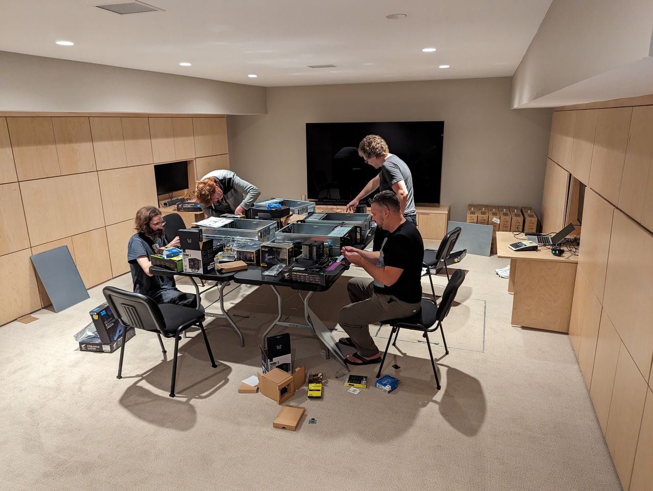 A number of people sit around a table, assembling PC hardware.