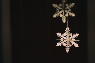 glittery paper snowflakes hanging from a Christmas tree