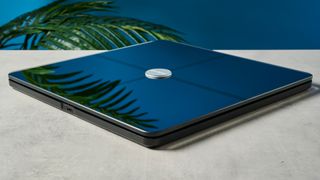 a modern black smart scale with a silver circle in its centre rests upon a light surface with a blue background