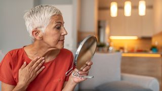 senipr woman looking at her skin in the mirror