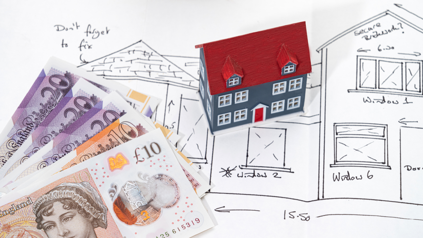 drawing of house with model of house and &pound;20 and &pound;10 notes lying on top of drawing