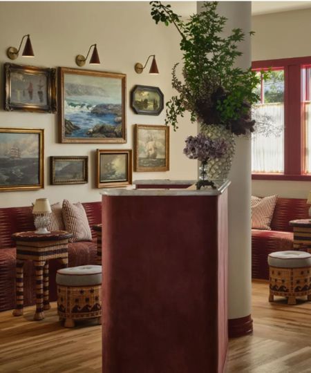 Hotel lobby with large gallery wall, upholstered seating, stools, vase of flowers