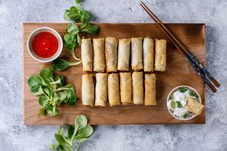 spring rolls on a board with dipping sauce