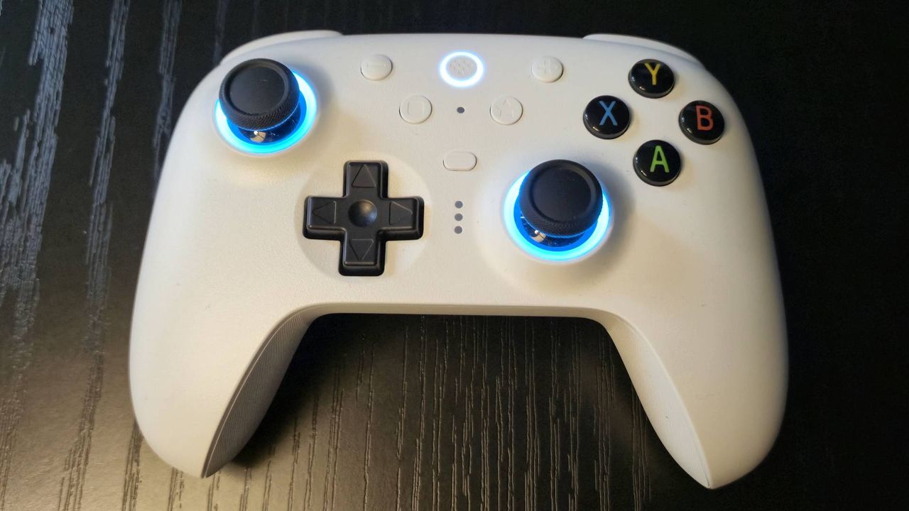 Image of a white controller with blue RGB sticks sitting on a black wooden table.