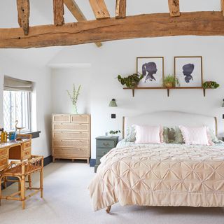 master bedroom with double bed, white walls and beamed vaulted ceiling as well as rattan furniture