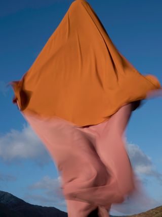 A person wrapped in orange fabric, jumping.