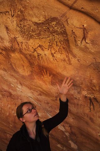 Emmanuelle Honoré holds up her hand in the Wadi Sūra II cave, located in the Egyptian part of the Libyan Desert.