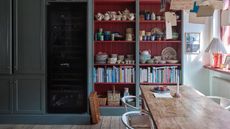 kitchen dining space with open shelving with red shiplap interior, books and crockery, dining table, to the left is mid blue cabinetry, Farrow & Ball : Asger Mortensen, Wester Agency