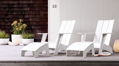 A pair of white Adirondack chairs outside a contemporary building