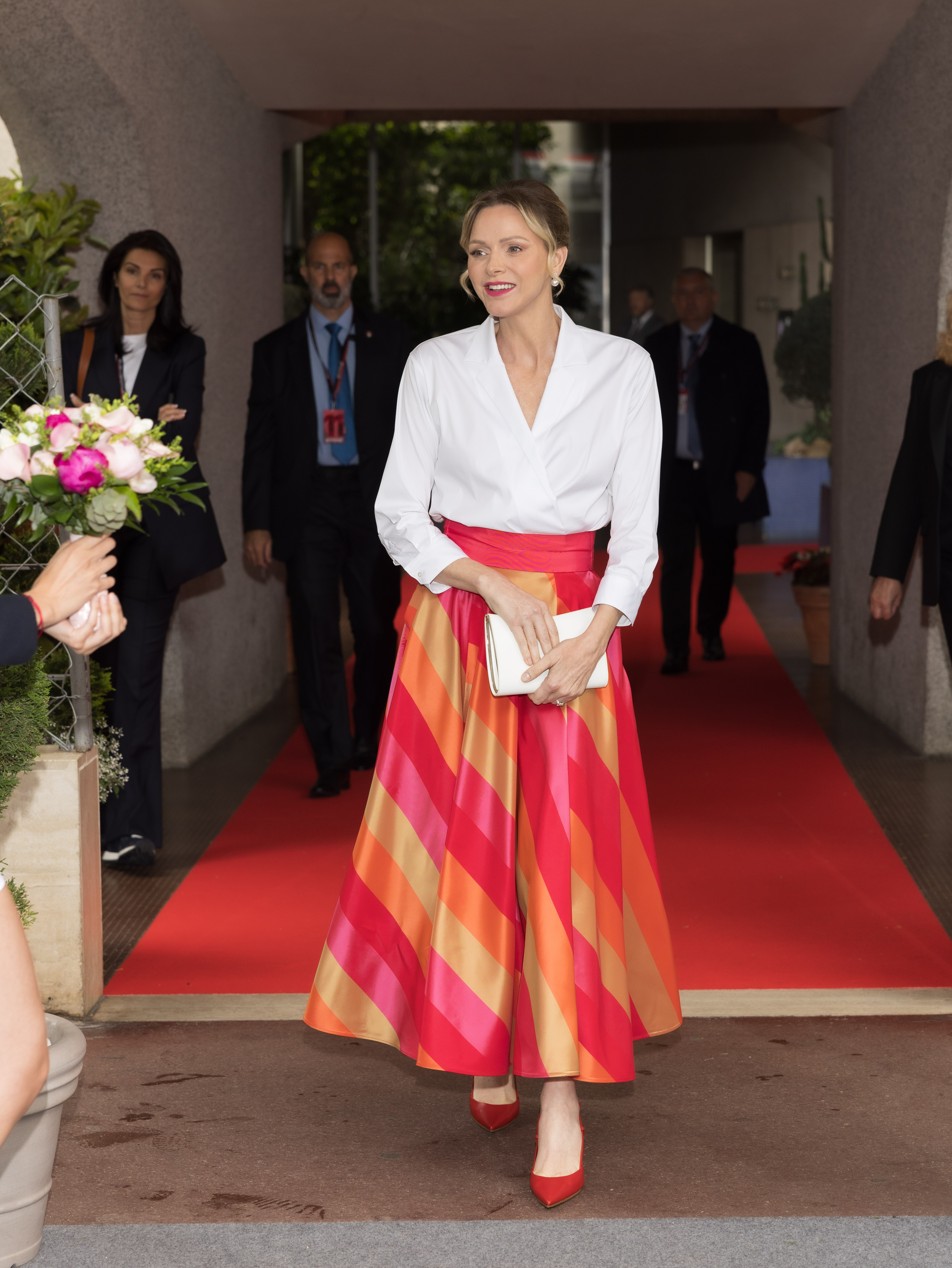 Princess Charlene in a white top and pink and orange striped skirt