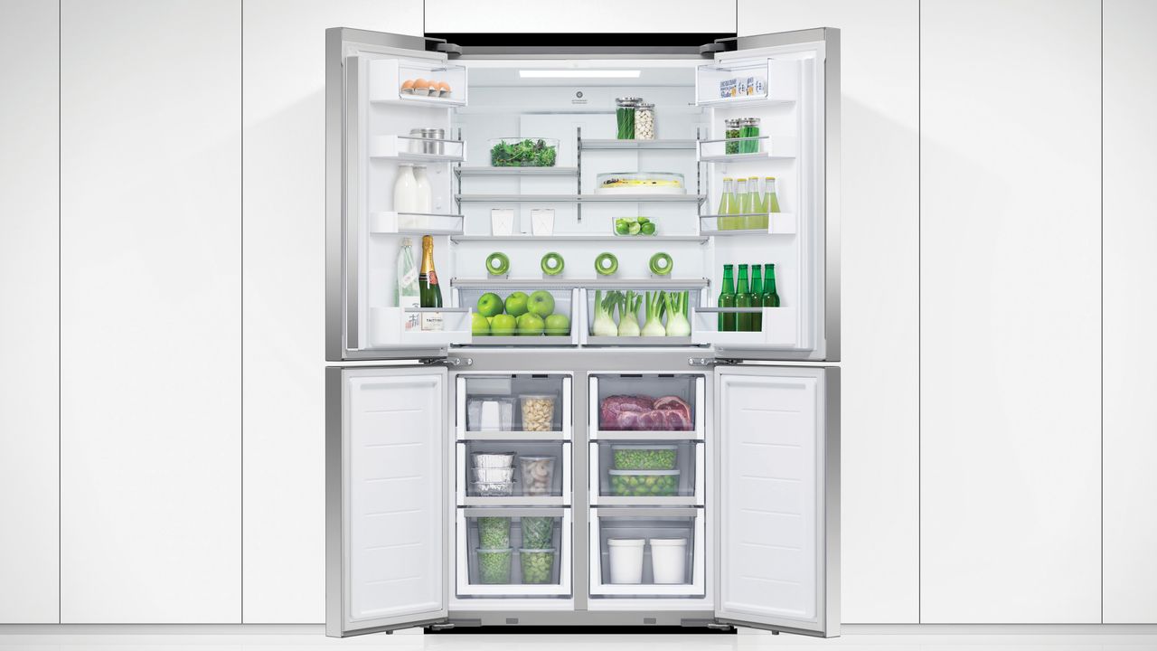 Fisher &amp; Paykel fridge freezer, one of the best fridge freezer options, with doors open in a white kitchen, showing lots of fruit, vegetables and drinks inside