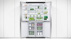 Fisher & Paykel fridge freezer, one of the best fridge freezer options, with doors open in a white kitchen, showing lots of fruit, vegetables and drinks inside