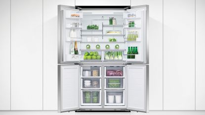 Fisher & Paykel fridge freezer, one of the best fridge freezer options, with doors open in a white kitchen, showing lots of fruit, vegetables and drinks inside