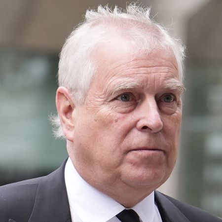 Prince Andrew wearing a suit and tie grimacing