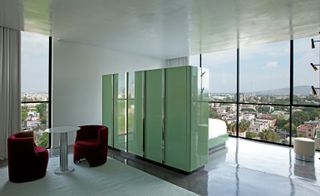 Bedroom and seating separated by green cupboard in room