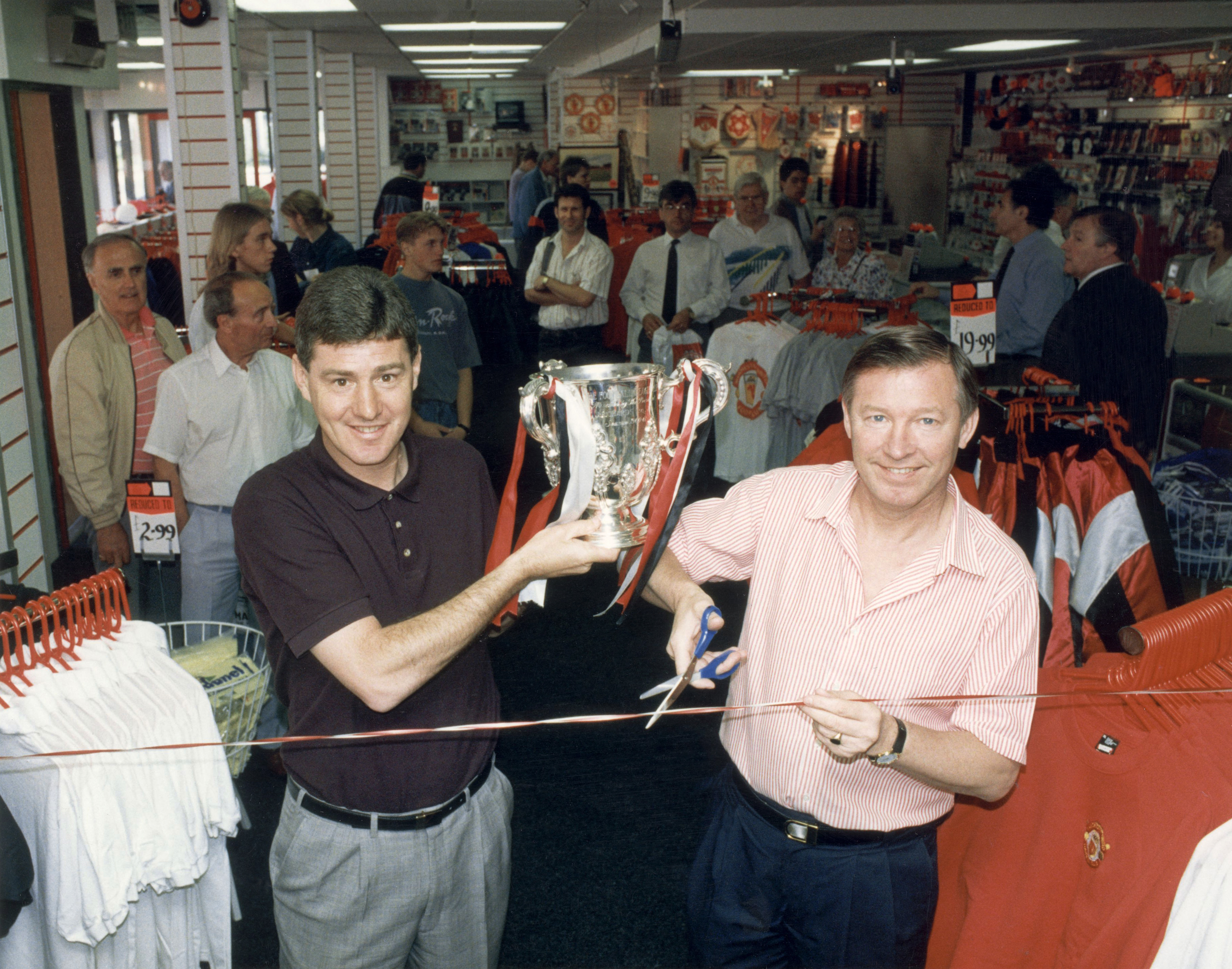 Alex Ferguson and assistant Brian Kidd pose with the League Cup trophy at an official Manchester United store in May 1992.