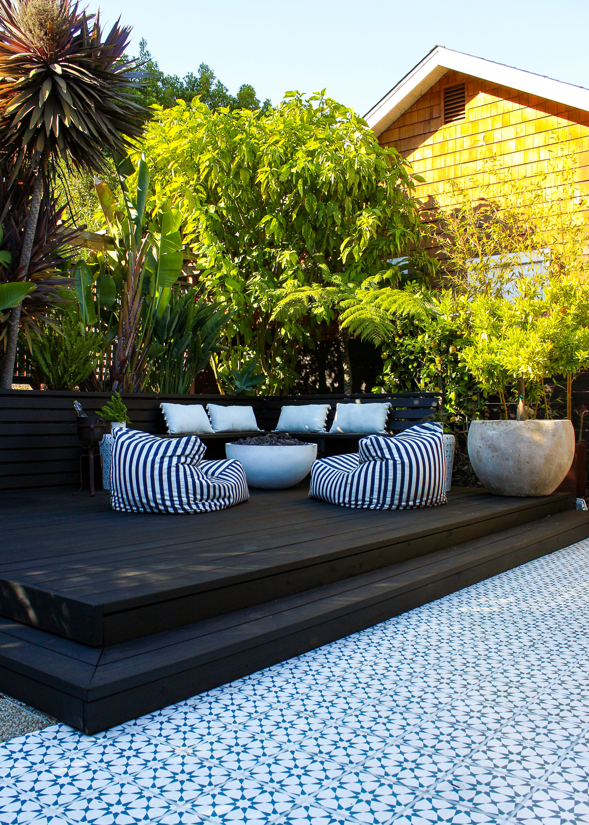 black deck with garden furniture and planter, with a backdrop of trees
