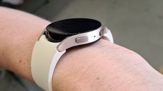 En Samsung Galaxy Watch 6 med ett vitt armband runt en handled.