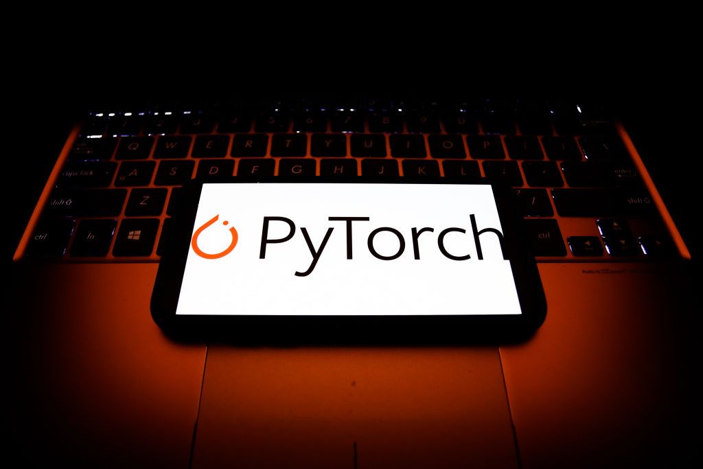 A smartphone resting on a laptop with the logo for PyTorch displayed