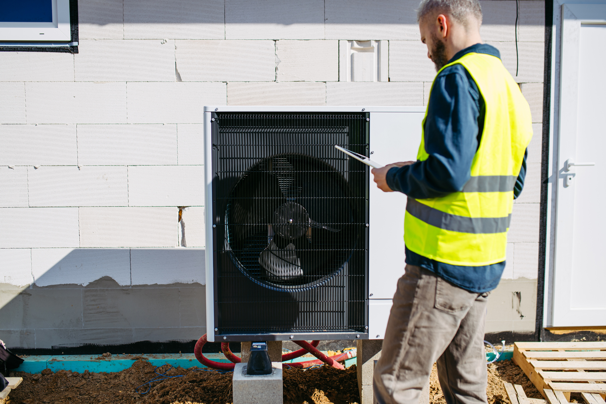 Technician inspecting outdoor heat pump unit during home installation