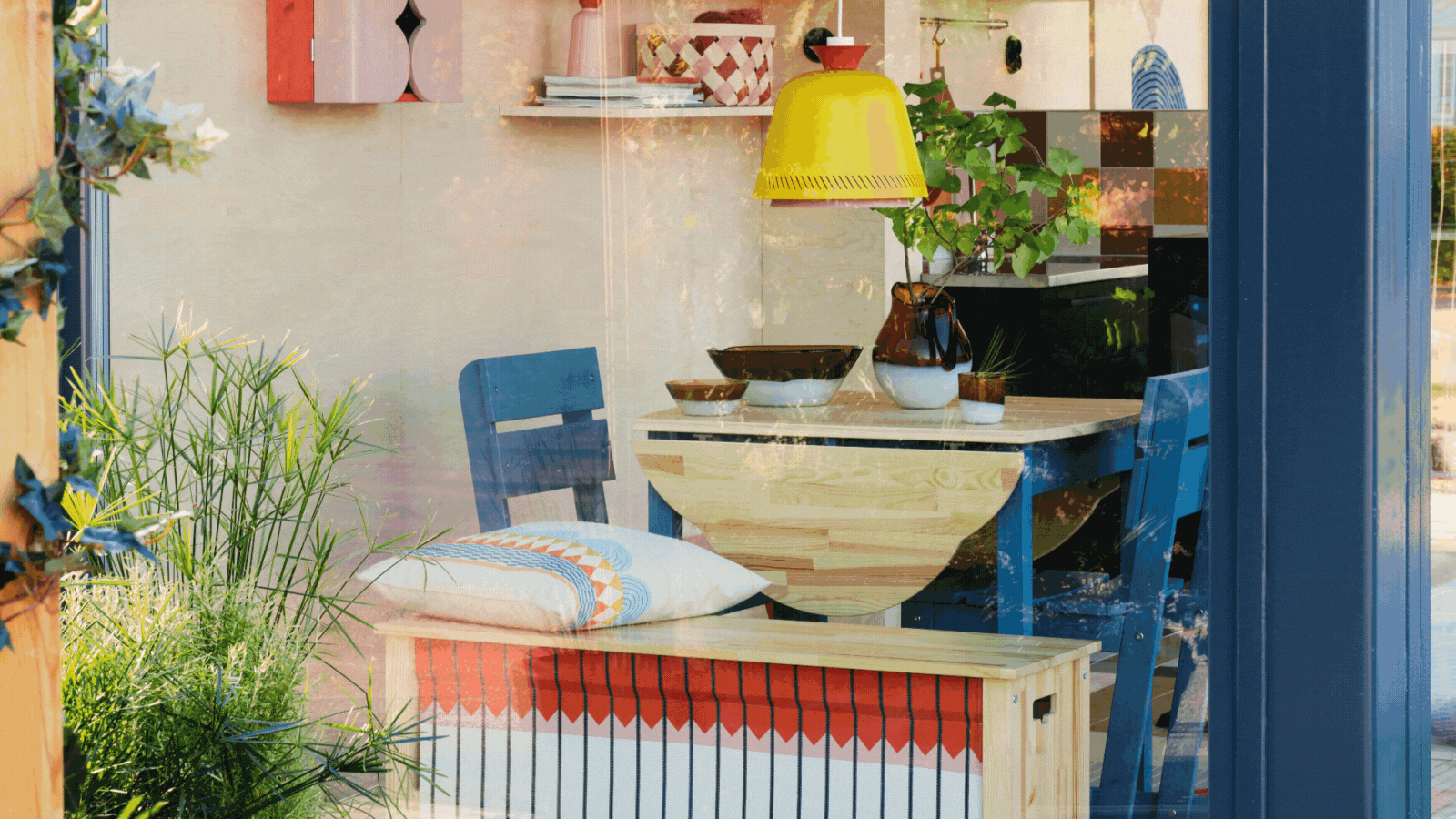 Three rotating images of Ikea's new folklore range. There is home decor like candle holders, cookware, pillows, and vases. Everything has a blue, pink, and orange color palette