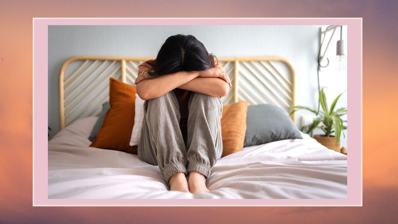 woman with her head in her lap crying in bed