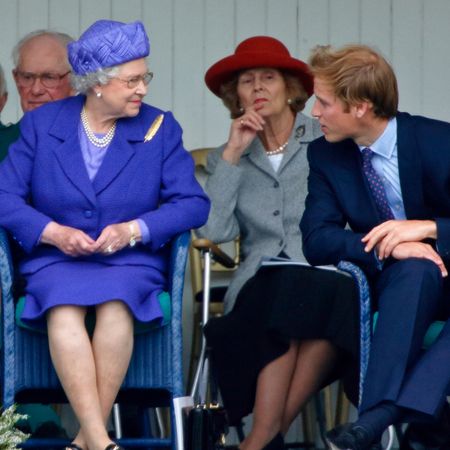 Queen Elizabeth wearing a purple suit smiling at Prince William