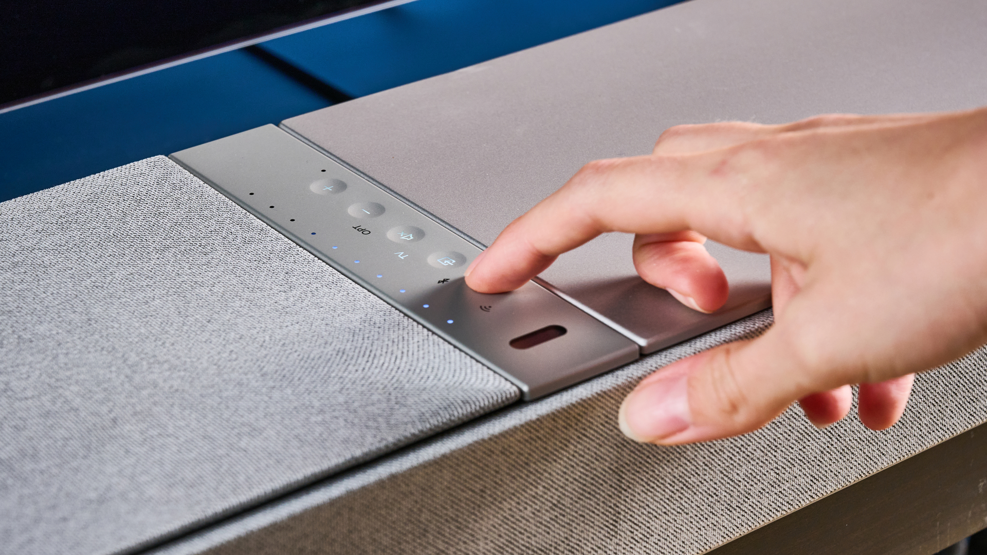 the KEF XIO soundbar in gray photographed with a TV and the Tom's Guide blue background
