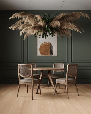 A dining room with a statement feather light, green walls and laminate floors
