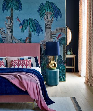 Mural in bedroom with palm trees, turrets and monkeys on midnight blue background, with bedding in blue and dusty pink.
