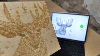 xTool P2 review; holding an engraved image up with an iPad in the background