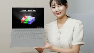 A promotional photo of a person holding a laptop sporting a tandem OLED display panel by LG