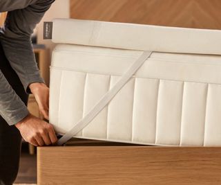 A man pulling the corner strap of a Tempur-Pedic Tempur-Adapt over a Tempur-Pedic mattress