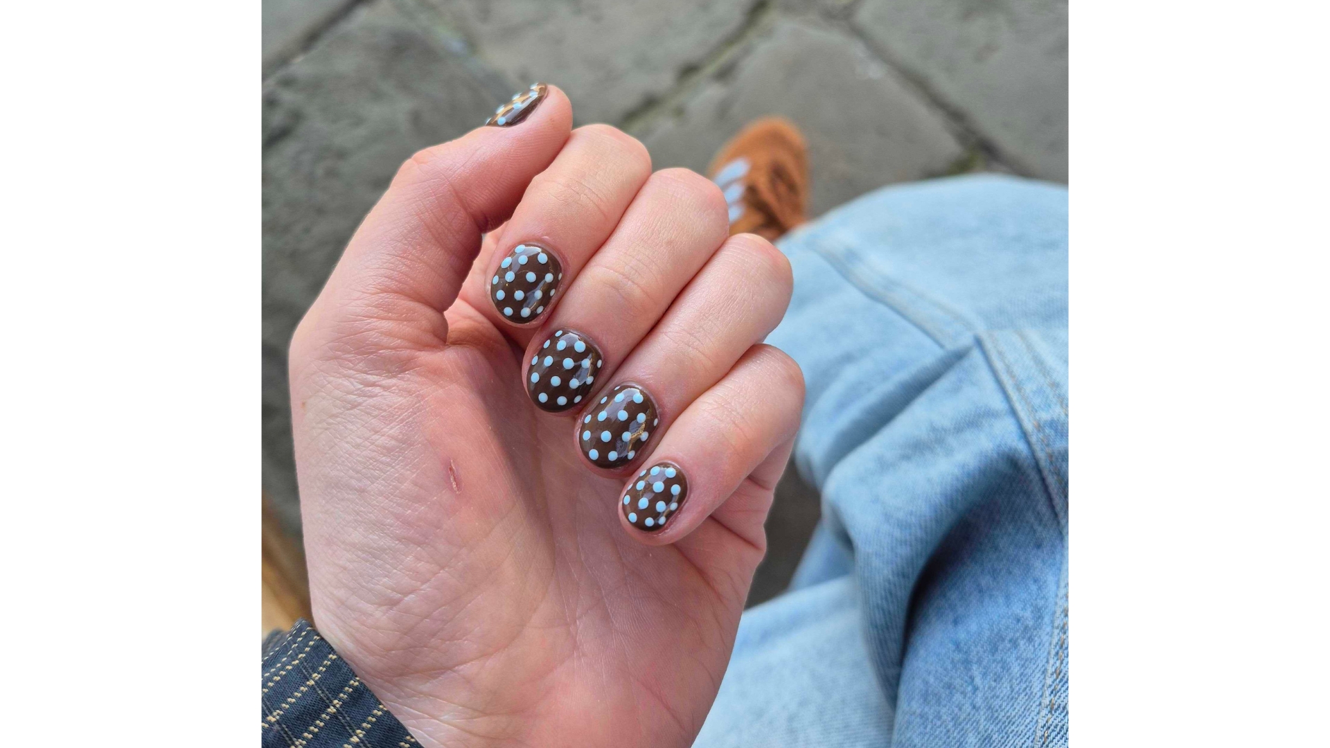 A close-up of Digital Beauty Writer, Naomi Jamieson's hand with blue and brown polka dot nails