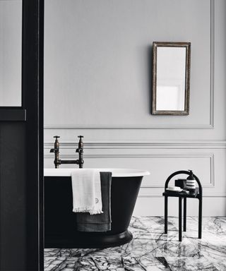 Grey panelled bathroom, mouldings, marble floor, black bath