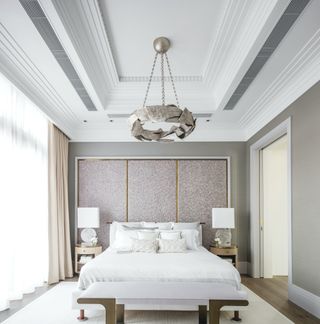 neutral bedroom with symmetrical lighting, white bedding, blush pink and gold textured backdrop behind the bed