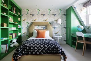 teen bedroom with green storage, parrot wallpaper, zebra blind, desk, globe, black and white blanket, orange bed pillow, gold single bed, white table/light