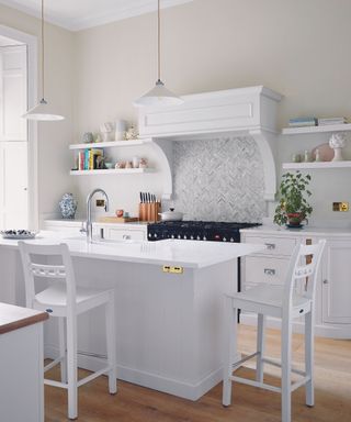 An all-white kitchen with a defining range hood and an island