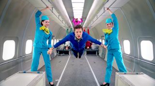 OK Go musician Damian Kulash (center) performs a scene from the band's music video ''Upside Down & Inside Out,'' in which tightly choreographed segments were filmed over the course of 21 parabolic flights that produced microgravity in the plane's cabin.
