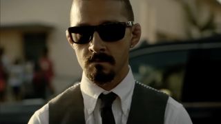 Shia LaBeouf wearing sunglasses, white collared shirt, tie and vest in The Tax Collector