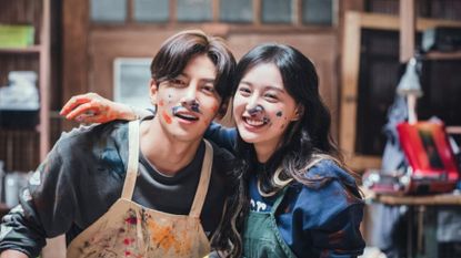 a couple covered in paint takes a picture in a craft studio, in the must-watch k-drama 'lovestruck in the city'
