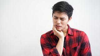 Can wisdom teeth grow back? Man holding his jaw in pain