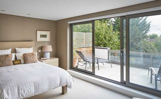 Sliding bedroom doors with grey frame in neutral space leading onto patio