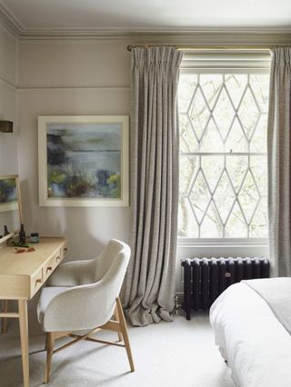 A neutral and white bedroom design. View of a desk corner with a window that gray curtains