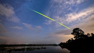 a green meteor above a lake
